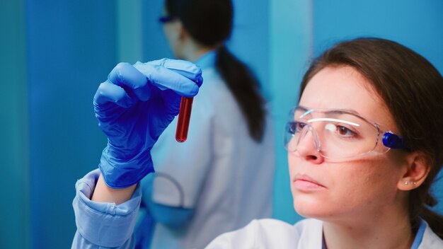 Wetenschappervrouw die bloedmonsters en vloeistof onderzoekt die in een modern uitgerust laboratorium werken
