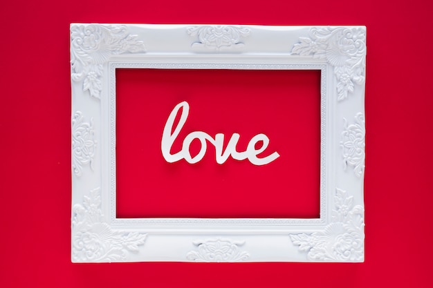 Gratis foto white love inscriptie in frame op rode tafel