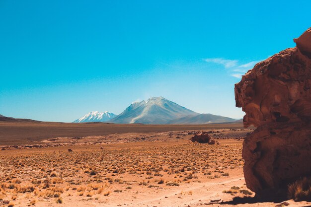 Wide shot van een klif en een berg in de woestijn met een heldere blauwe lucht op een zonnige dag