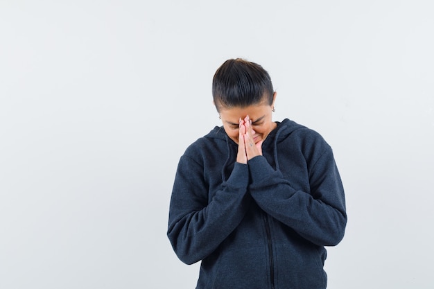 Wijfje dat namaste-gebaar in hoodie toont en hoopvol kijkt. vooraanzicht.