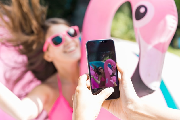Wijfje die mooie tienervrouw op opblaasbare flamingo fotograferen