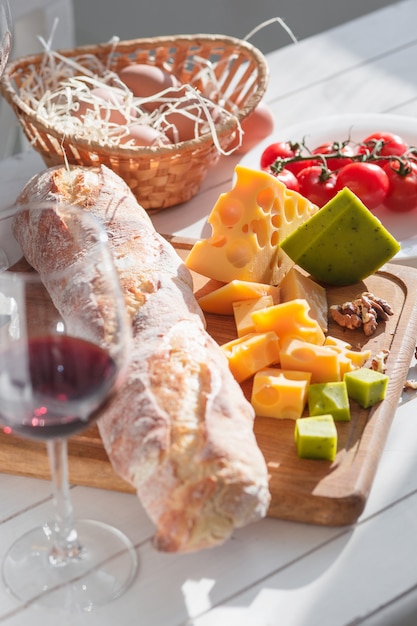 Wijn, stokbrood en kaas op houten tafel