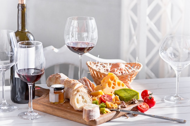 Wijn, stokbrood en kaas op houten tafel