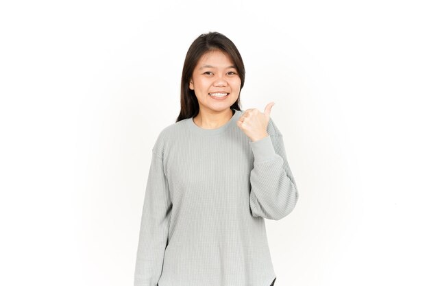 Wijzend product met duim van mooie aziatische vrouw geïsoleerd op een witte achtergrond
