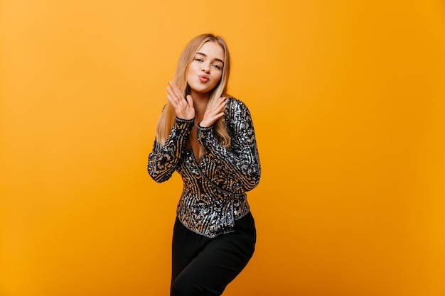 Winderige blanke vrouw in stijlvolle kleding dansen op oranje. Het belangstellende vrouw stellen met uitdrukking van het kussen gezicht.