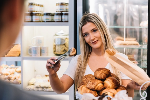 Gratis foto winkelbediende die croissantzak voorbereidt