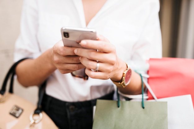 Gratis foto winkelend meisje dat haar mobiele telefoon met behulp van