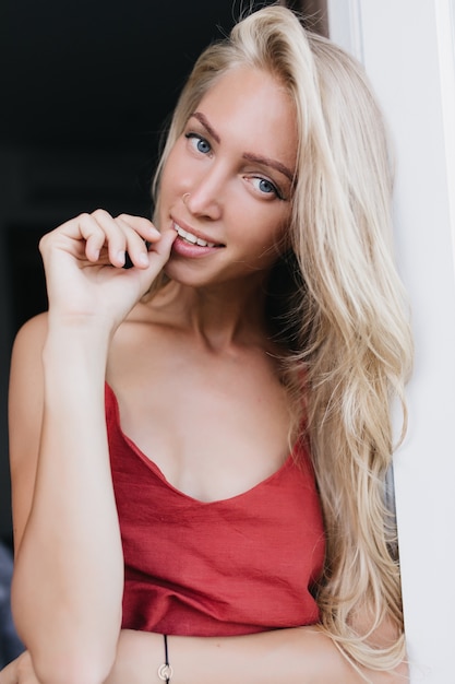 Winsome meisje met lang blond haar speels poseren in zijden nachtkleding. vrouwelijk model in pyjama