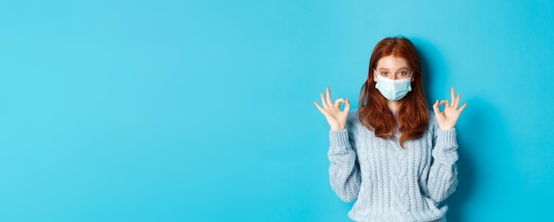 Winter covid en social distancing concept stelde jonge roodharige vrouw met gezichtsmasker tevreden