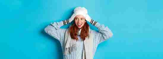 Gratis foto winter- en vakantieconcept gelukkig roodharig meisje in muts, muts, sjaal en handschoenen die er goed en glimlachend uitziet