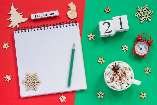 Winter samenstelling. houten kalender 21 december beker cacao met marshmallow, lege open notitieblok met potlood,