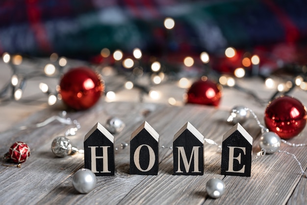 Wintercompositie met het decoratieve woord huis en kerstballen op een onscherpe achtergrond met bokeh.