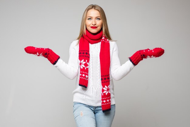 Winterconceptfoto van een aangename blonde dame die haar handen opzij houdt en sjaal en wanten draagt. vakantie concept