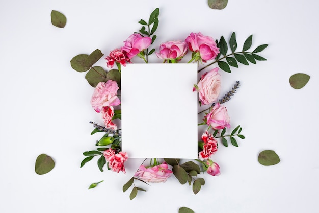 Gratis foto wit blanco papier op mooie bloemen over de witte achtergrond