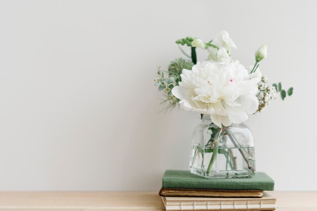 Wit bloemboeket in een opgeruimde vaas op een stapel boeken