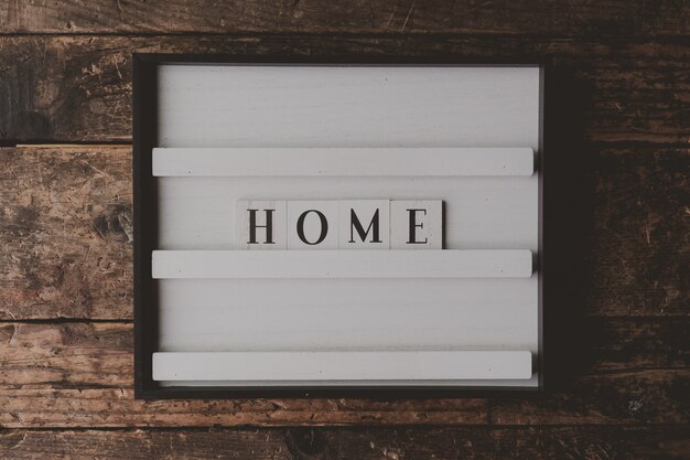 Wit bord met een schrijven "Home" op het op een houten bruine muur