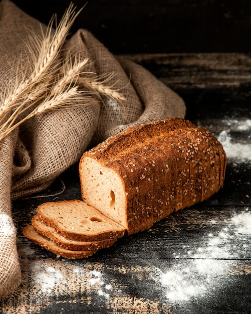 wit brood gesneden brood met zaden, tarwe en meel op tafel