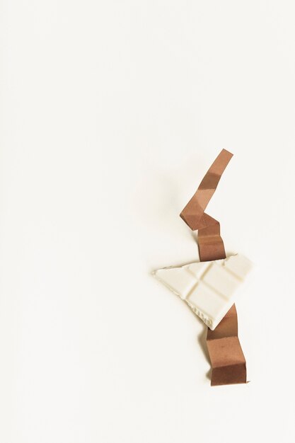 Wit chocoladestuk op gevouwen bruin kaartdocument tegen witte achtergrond