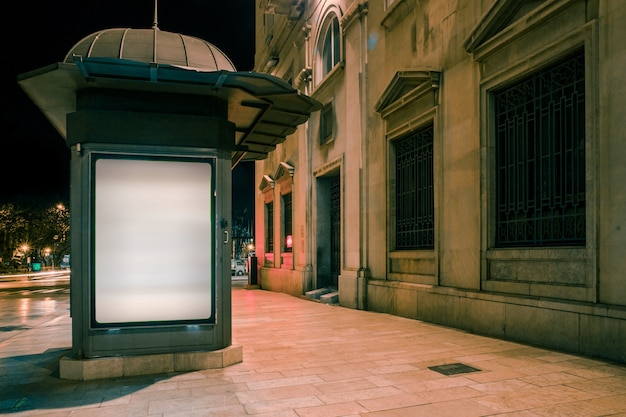 Wit verlicht leeg reclamebord op voetpad bij nacht