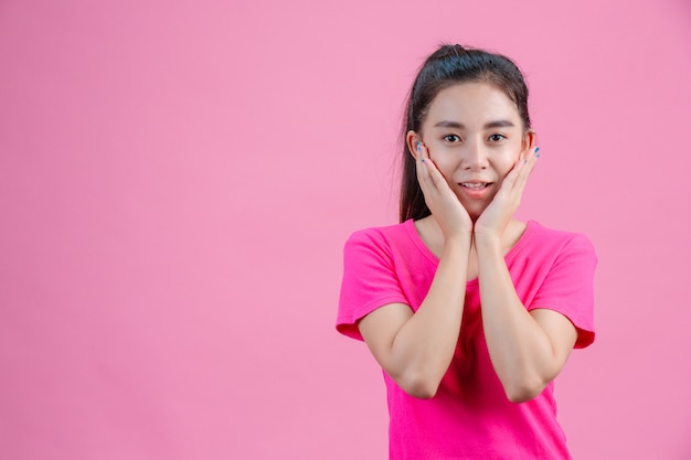 Witte Aziatische vrouwen dragen roze shirts. Met beide handen het gezicht op het roze houdend.