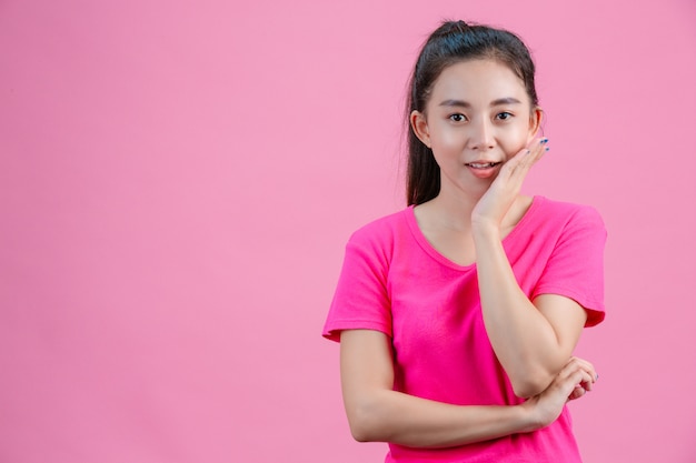 Witte Aziatische vrouwen dragen roze shirts. Steek zijn linkerhand in zijn gezicht op het roze.