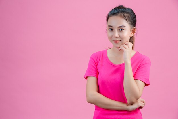 Witte Aziatische vrouwen dragen roze shirts. Steek zijn linkerhand in zijn gezicht op het roze.