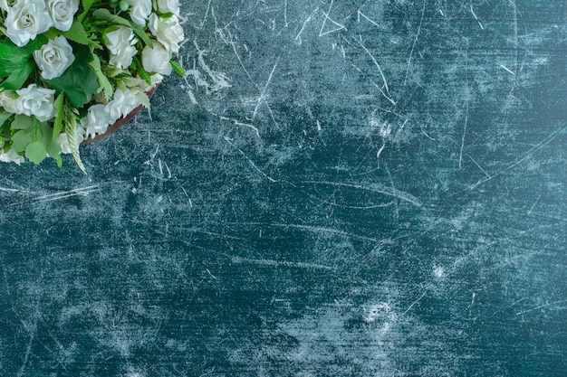 Witte bloemen in een houten plaat, op de blauwe achtergrond.