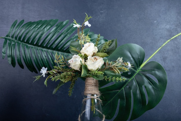 Witte bloemen in keramische vaas op donkere muur.