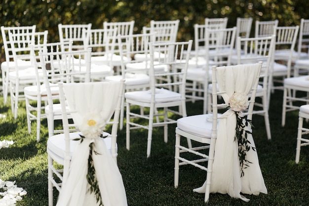 Witte bloemen met groene takken versieren stoelen