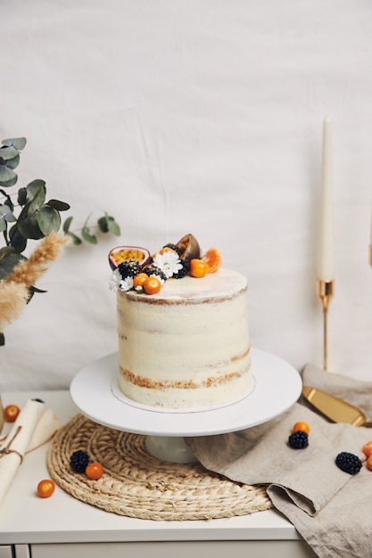 Witte cake met bessen en passievruchten naast een plant