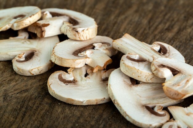 Witte champignons gesneden op bruin houten bureau