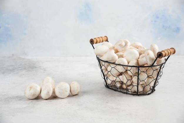 Witte champignons in een metalen dienblad op marmeren tafel.