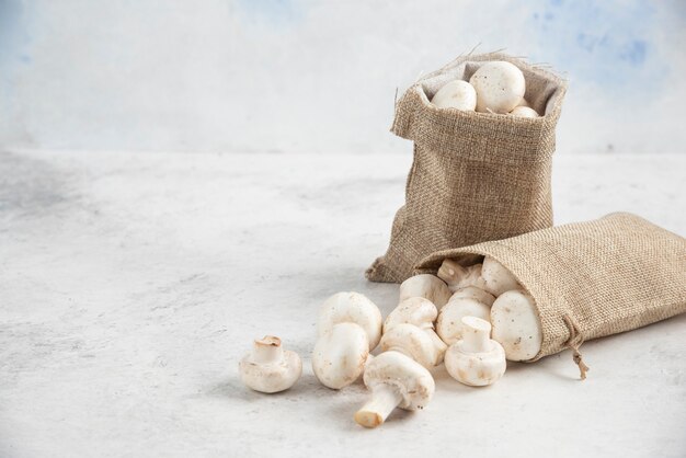 Witte champignons in rustieke manden op marmeren tafel.