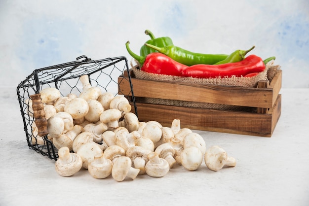 Witte champignons met rode en groene chilipepers in een houten dienblad.