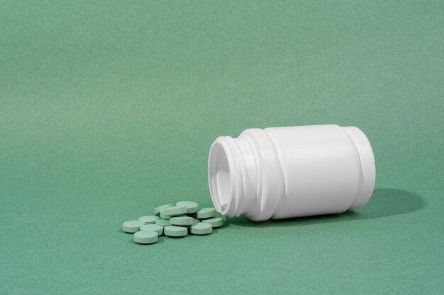 Witte container met groene pillen hoge hoek