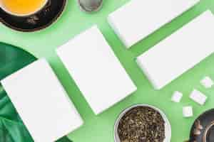 Gratis foto witte dozen met gezonde thee met kruiden en suikerkubussen op groene achtergrond