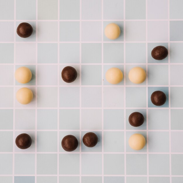 Witte en donkere chocolade ballen op geruite achtergrond