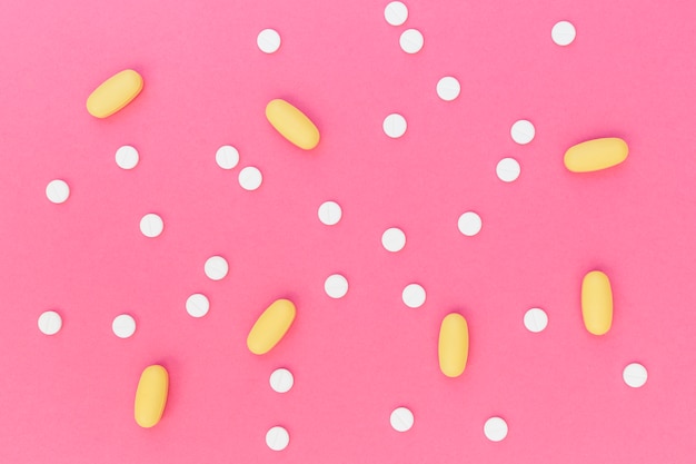 Witte en gele pillen op roze achtergrond
