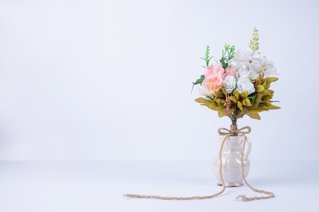 Witte en roze bloemen in keramische vaas op wit.