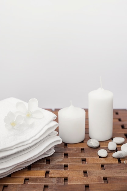 Witte handdoek; bloemen; kaarsen en kiezels op houten oppervlak