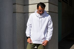 Gratis foto witte hoodie op man met groene broek in de stad