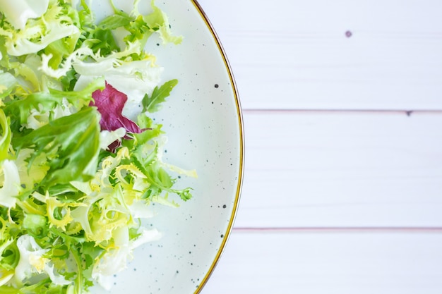 Witte keramische plaat met verse salade op houten oppervlak