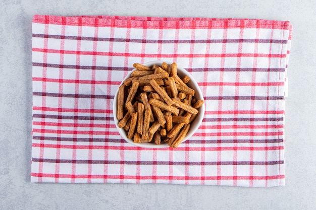 Witte kom krokante stokcrackers op stenen ondergrond.