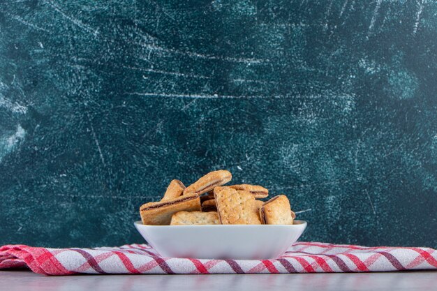 Witte kom smakelijke krokante crackers op stenen achtergrond.