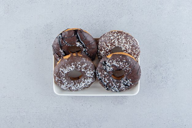Witte kom van vier chocolade donuts op stenen achtergrond. Hoge kwaliteit foto