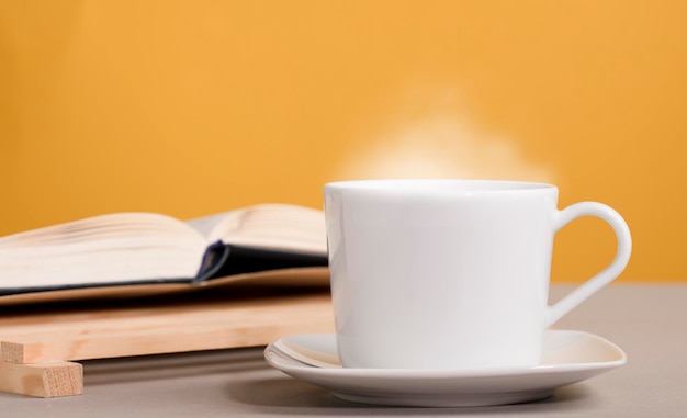 Witte kop koffie of thee met hete stoom op tafel met boeken