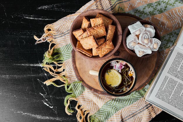 Witte marshmallows in een metalen beker met kruidenthee en crackers.