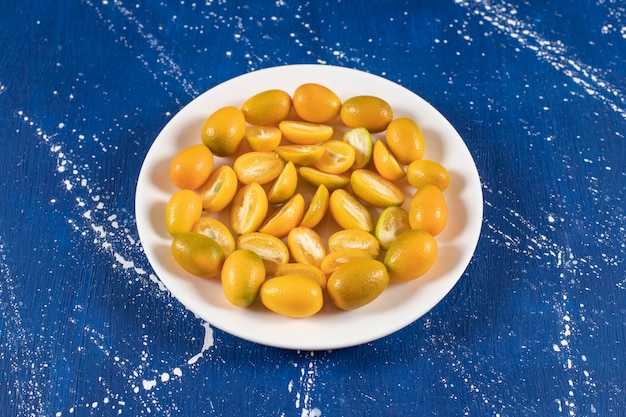 Witte plaat met gesneden verse kumquatvruchten op marmeren oppervlak