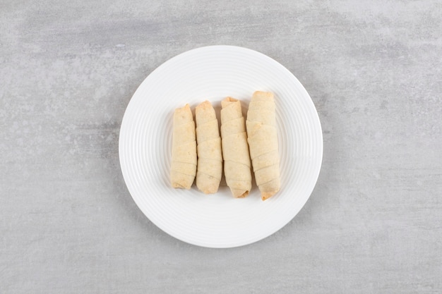 Witte plaat van traditionele zoete mutaki op stenen tafel.