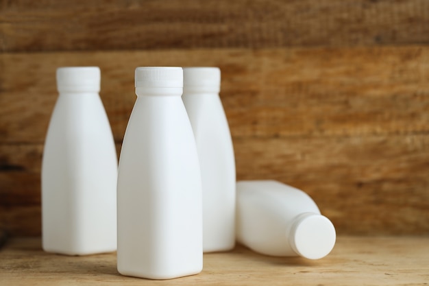 Witte plastic melk flessen op retro houten tafel achtergrond